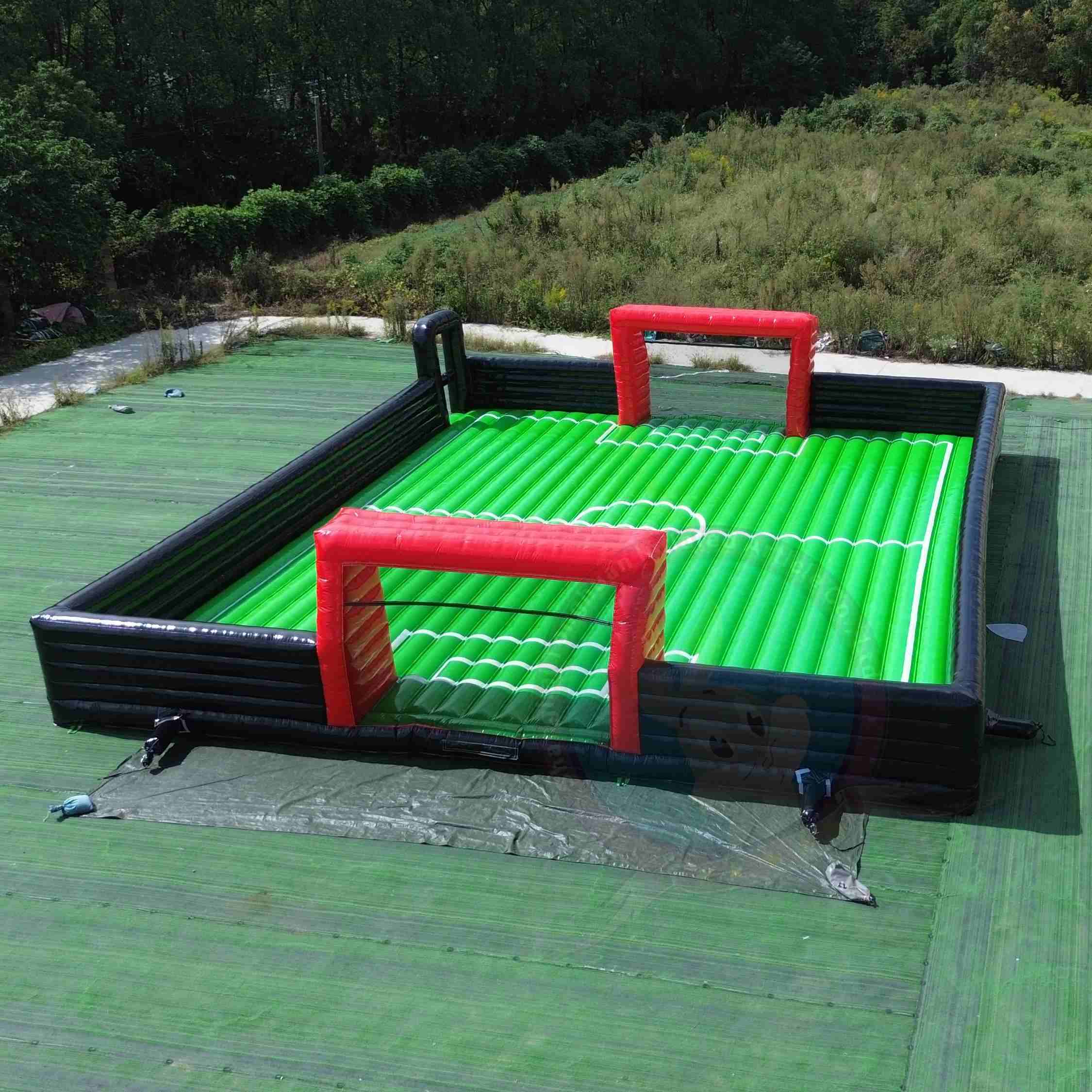 PRODUCT CORE HIGHLIGHTS  · Inflatable soccer field design combines football play bouncing fun and enclosed safety structure for active group entertainment  · Large custom size options support indoor halls outdoor lawns schools clubs events and commercial amusement projects  · Soft inflatable walls and goal areas help create a safer play space for children teens and interactive participants  · Durable PVC construction supports repeated use easy cleaning convenient storage and fast setup for rental operations  · Suitable for football training family activities team games carnival programs sports events and inflatable playground business use